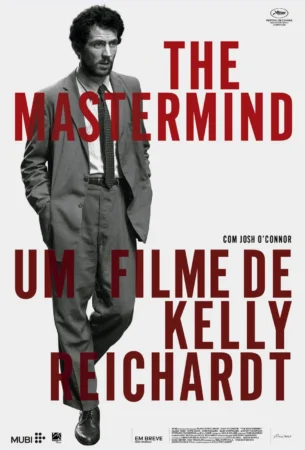 Pôster oficial em português do filme "The Mastermind", mostrando o ator Josh O'Connor de terno em preto e branco com grandes letras vermelhas indicando a direção de Kelly Reichardt.