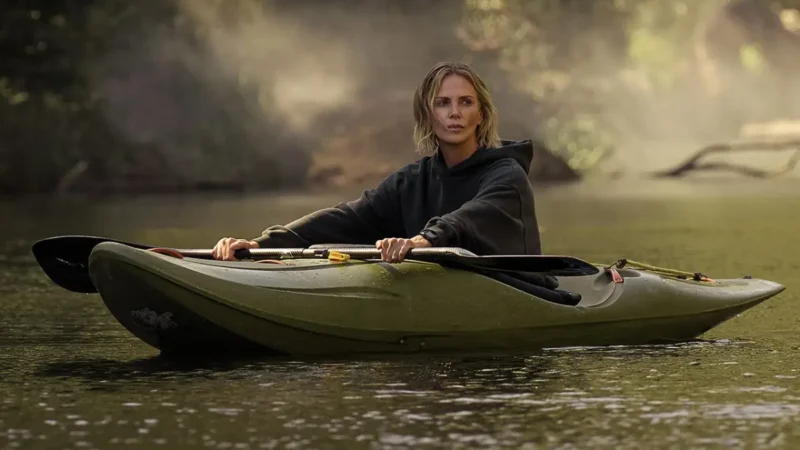 Charlize Theron em um caiaque no rio em cena de O Jogo do Predador, crítica e suspense na Netflix.