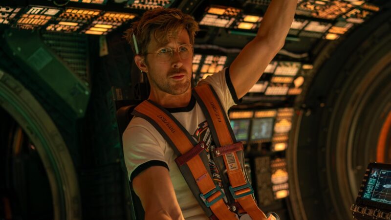 Ryan Gosling como Ryland Grace no cockpit da nave Hail Mary em Devoradores de Estrelas (2026), iluminado por tons quentes e laranjas.