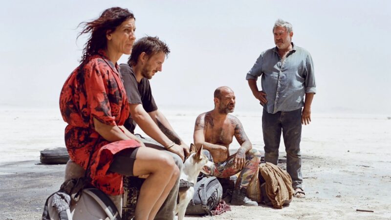 Cena do filme Sirât, drama indicado ao Oscar, mostrando um grupo de pessoas e um cachorro em uma paisagem desértica e ensolarada, destaque das estreias da semana