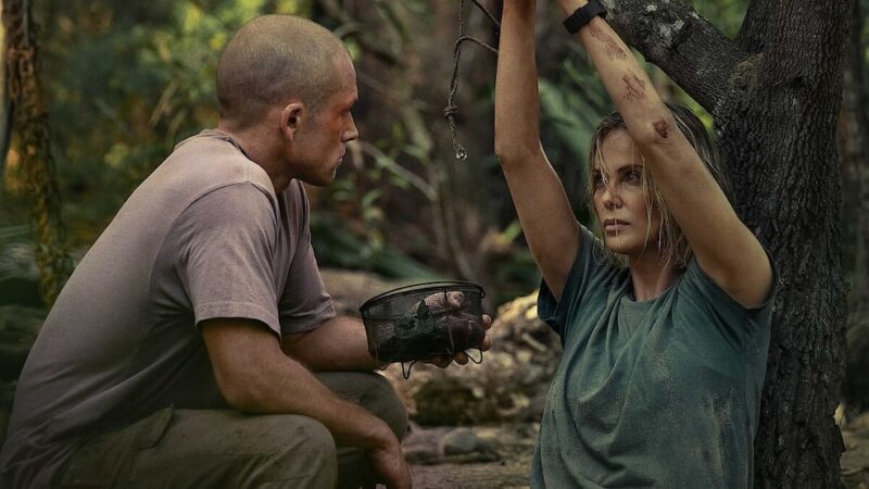 Taron Egerton observa Charlize Theron capturada em cena de O Jogo do Predador, crítica e suspense da Netflix