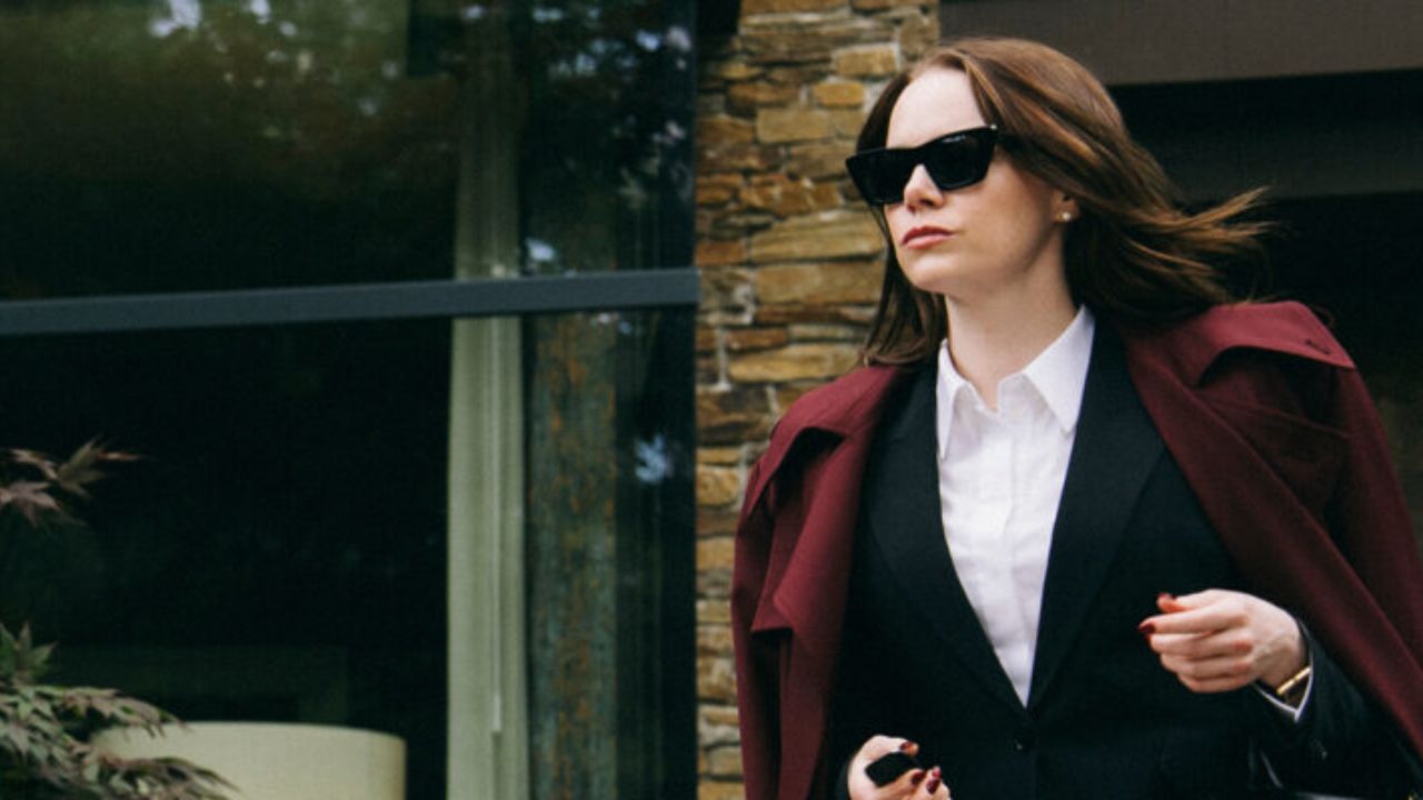 O que assistir nos streamings: a atriz Emma Stone usando óculos escuros e sobretudo vinho em cena do filme Bugonia.