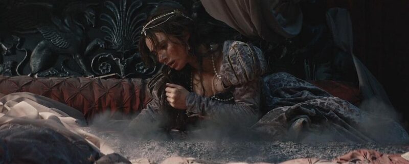 Drácula de Luc Besson: cena dramática com personagem feminina sobre a cama em meio a cinzas e fumaça.