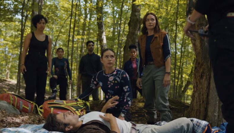Equipe médica de resgate da série SkyMed reunida na floresta ao redor de um paciente deitado, em cena das estreias nos streamings da semana.