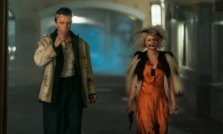 Christian Bale como o Monstro de Frankenstein e Jessie Buckley como A Noiva caminhando por uma rua escura e esfumaçada no filme de Maggie Gyllenhaal.