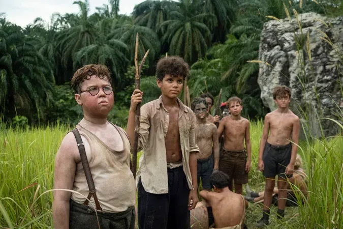 Grupo de meninos sobreviventes em uma ilha tropical na minissérie O Senhor das Moscas da Netflix, destacando os personagens Piggy e Ralph