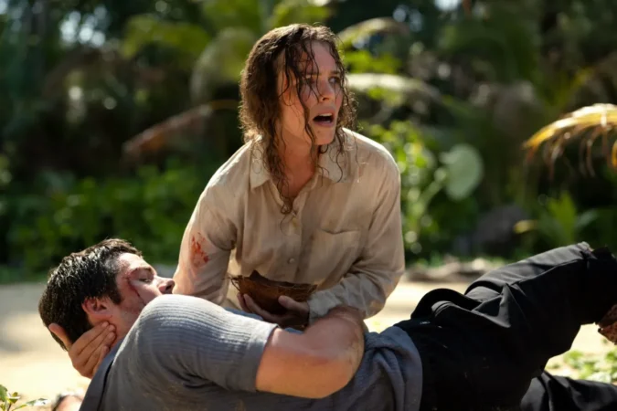 Rachel McAdams desesperada socorrendo Dylan O'Brien ferido em uma praia tropical no filme Socorro!.