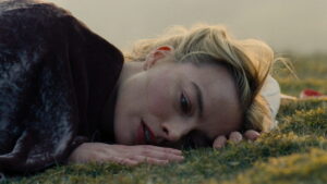 Margot Robbie como Catherine em cena de O Morro dos Ventos Uivantes 2026 deitada na grama