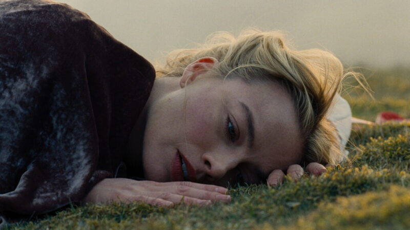 Margot Robbie como Catherine em cena de O Morro dos Ventos Uivantes 2026 deitada na grama