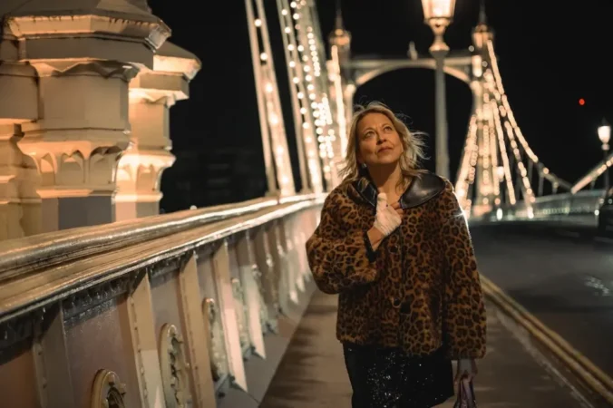 Nicola Walker caminhando em uma ponte iluminada à noite na série Alice e Steve no Disney+.