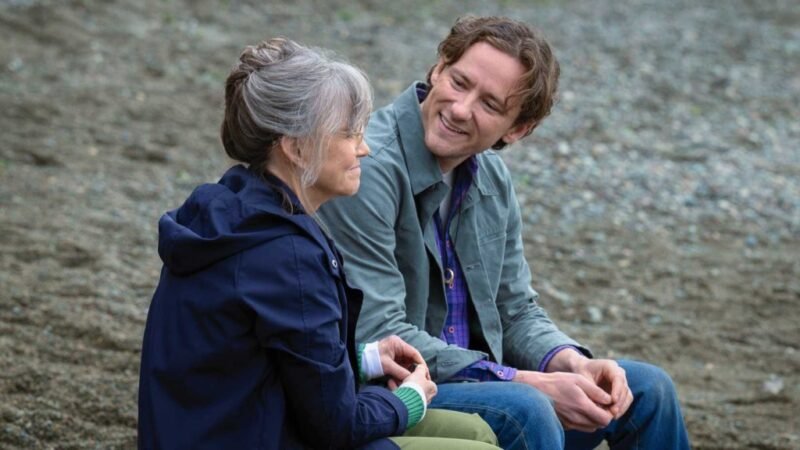 Sally Field e Thomas Mann conversando sentados em uma praia de cascalho, refletindo sobre o significado de Criaturas Extraordinariamente Brilhantes.