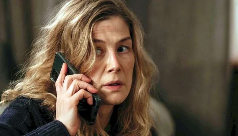 Close da atriz Rosamund Pike ao telefone em cena de Hallow Road: Caminho Sem Volta.
