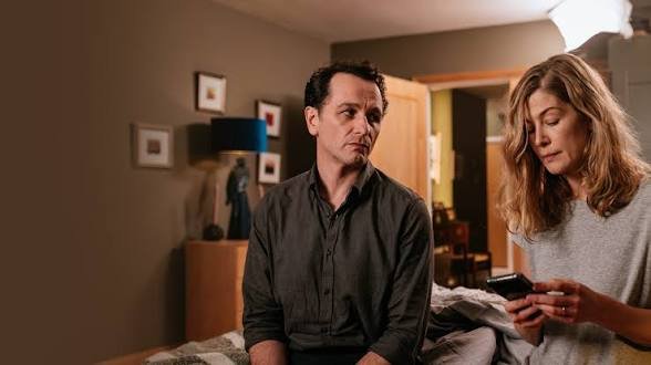 Matthew Rhys e Rosamund Pike no quarto investigando mensagens em Hallow Road: Caminho Sem Volta.