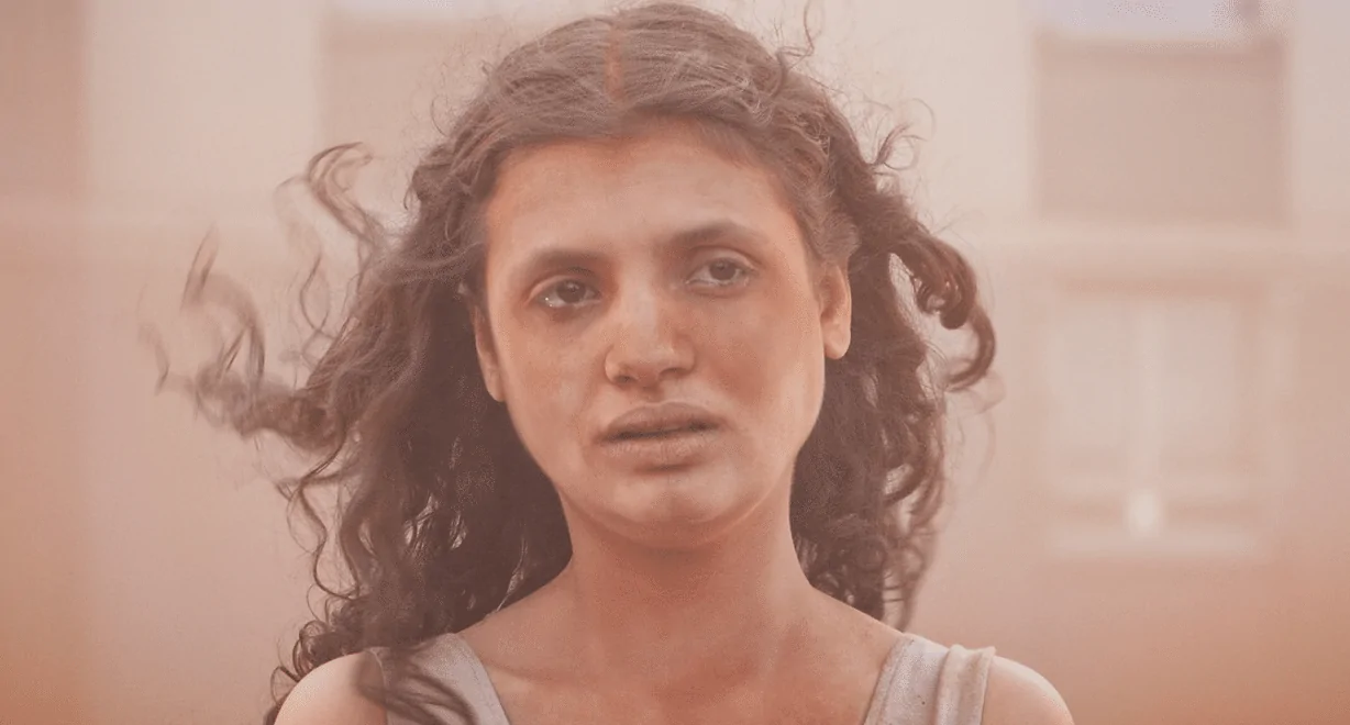 Mélissa Boros com semblante exausto em cena tomada por poeira no filme Alpha, destaque entre os lançamentos de julho.