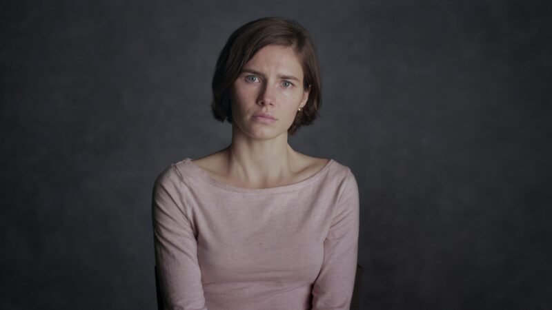 Amanda Knox olhando séria e fixamente para a câmera em plano médio durante entrevista para seu documentário de true crime na Netflix.