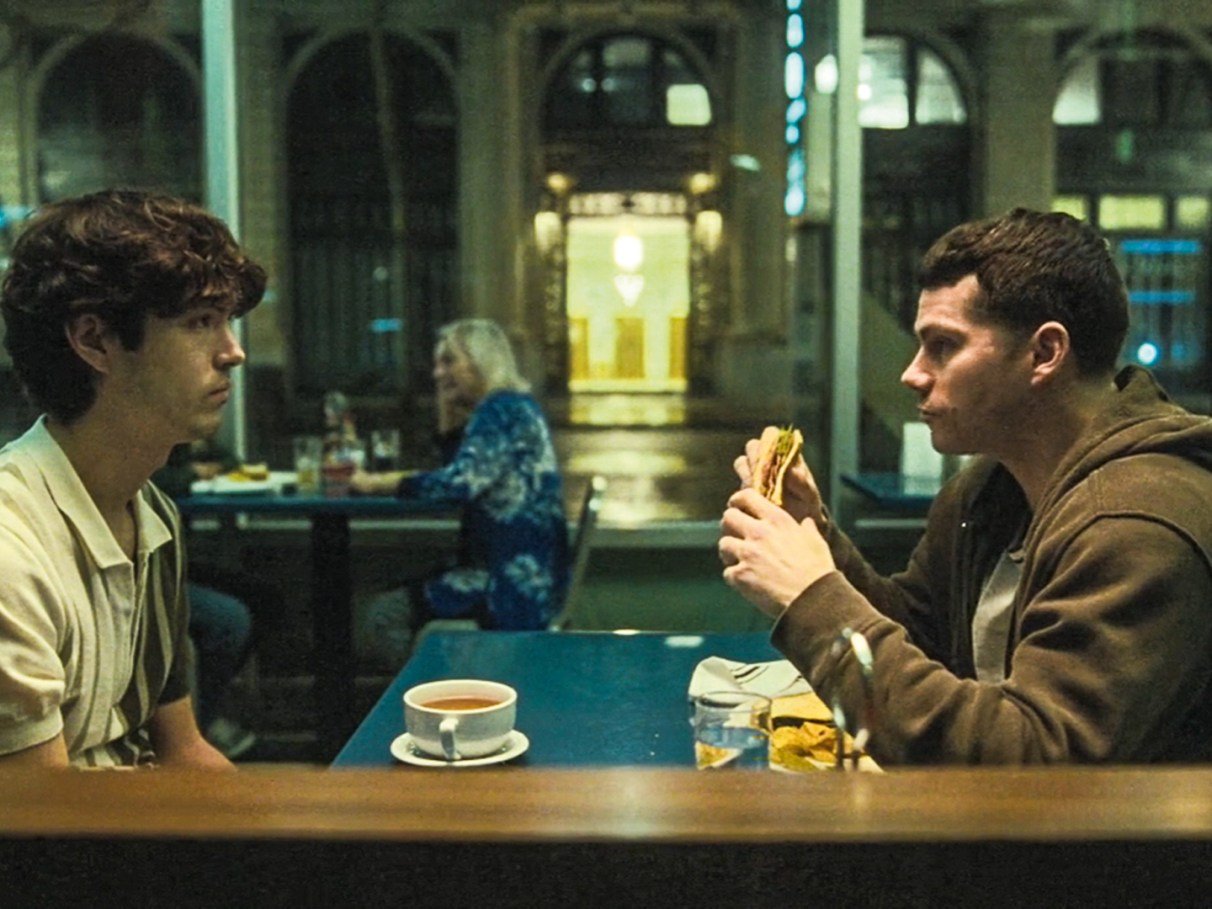 Os atores James Sweeney e Dylan O'Brien conversando em uma lanchonete no filme Twinless.