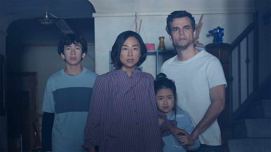 Os atores Greta Lee e Wagner Moura com expressão de pavor ao lado de dois filhos em uma sala escura no filme A Última Casa, destaque entre as estreias de agosto no streaming.
