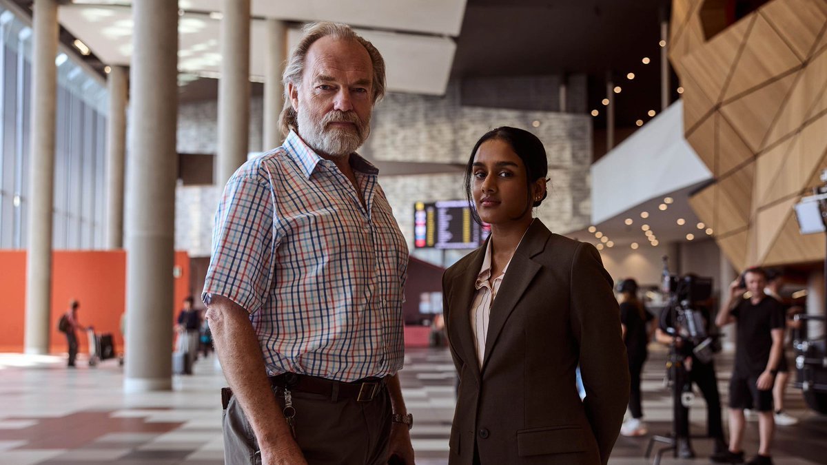 Hugo Weaving em cena no saguão de O Capelão do Aeroporto, uma das novidades entre os lançamentos de agosto.