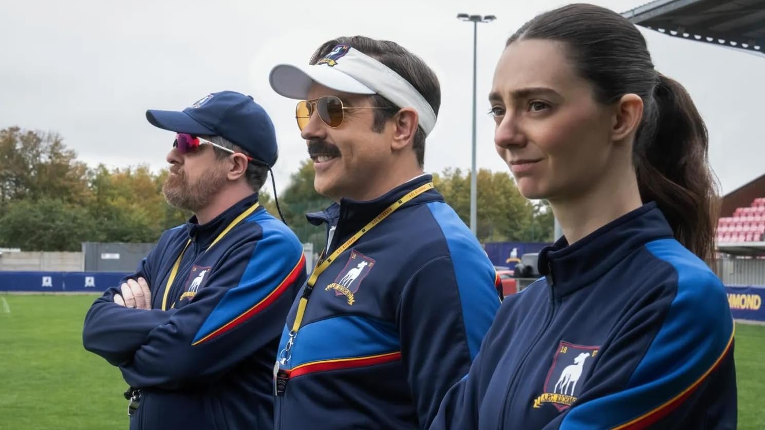 Treinadores Beard, Ted Lasso e a personagem Shannon no campo de futebol na quarta temporada, uma das principais estreias de agosto no streaming.