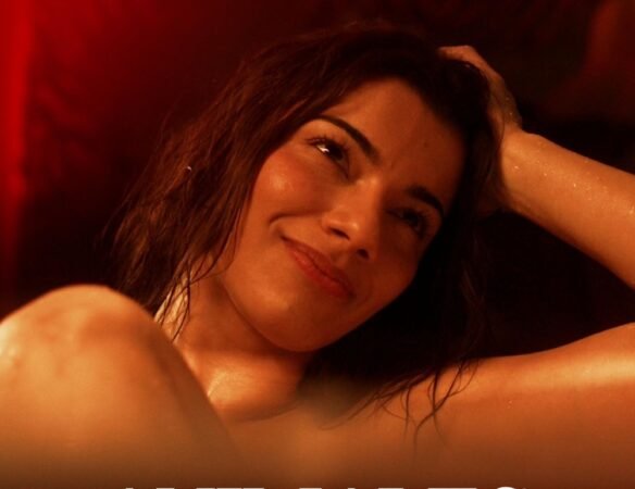 Mulher sorrindo com cabelo molhado e a mão na cabeça em um ambiente de luz vermelha quente na série Animais, fechando as estreias de agosto no streaming.