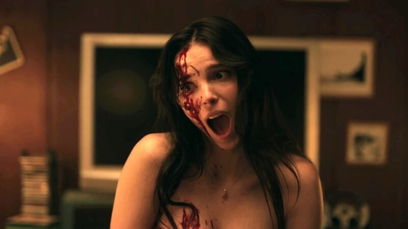 A atriz Inde Navarrette gritando com o rosto ensanguentado em cena clímax do filme Obsessão.