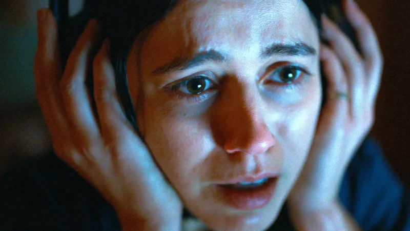 Rosto de mulher chorando e expressando desespero enquanto aperta os fones de ouvido contra as orelhas no filme Undertone