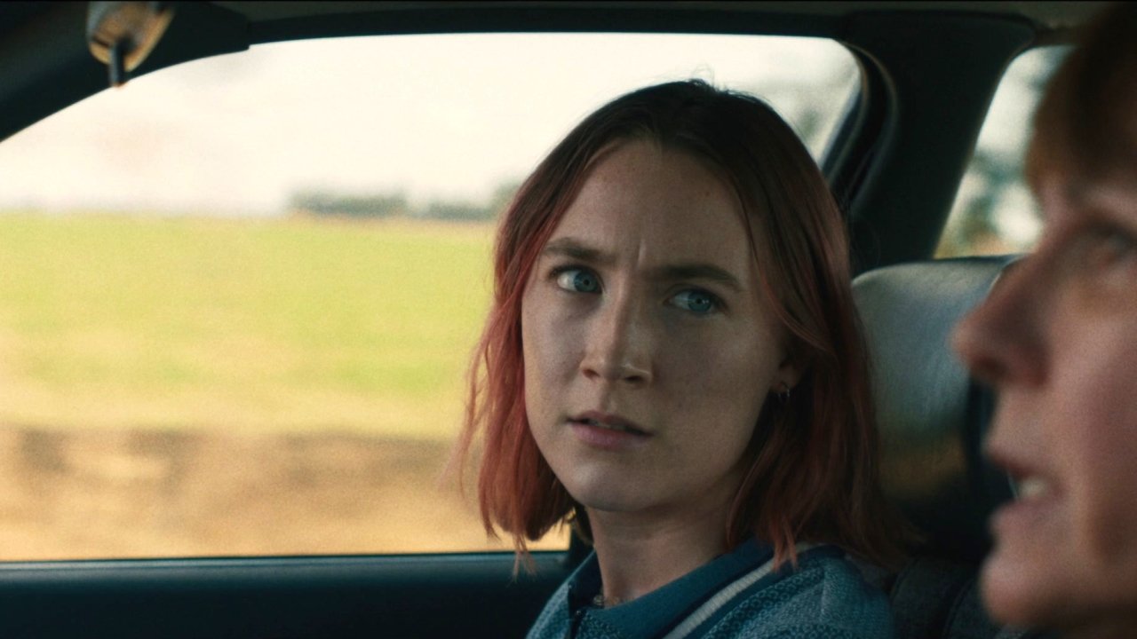 Lady Bird sentada no banco do passageiro de um carro em Lady Bird: A Hora de Voar