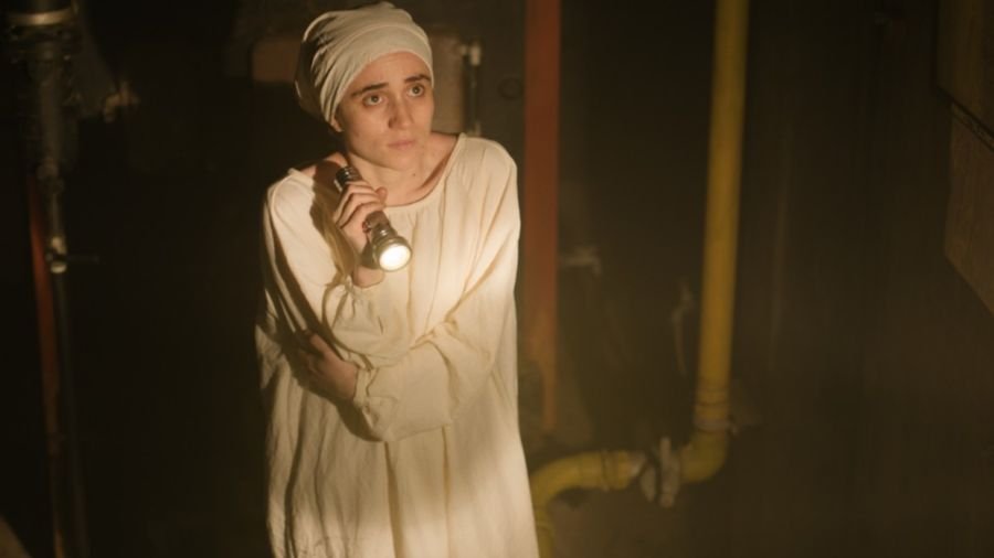 Clara segura uma lanterna em um ambiente escuro na série Confinada