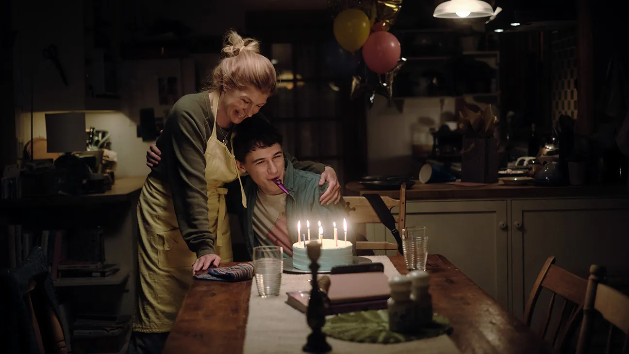 Ellen e Sonny comemoram um aniversário diante de um bolo com velas acesas na série Fingida (2026), apresentada no guia de episódios de Fingida.