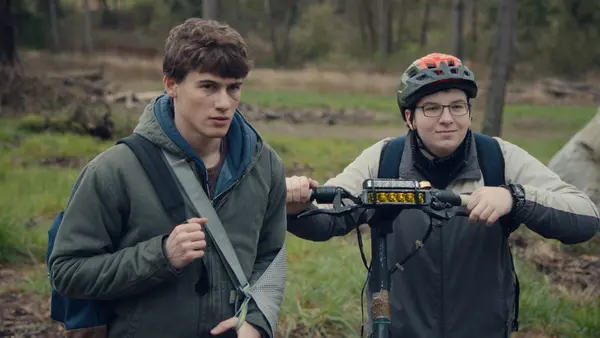 Dois jovens conversam ao lado de uma bicicleta na série Fingida, uma das novidades de outubro no Disney+.